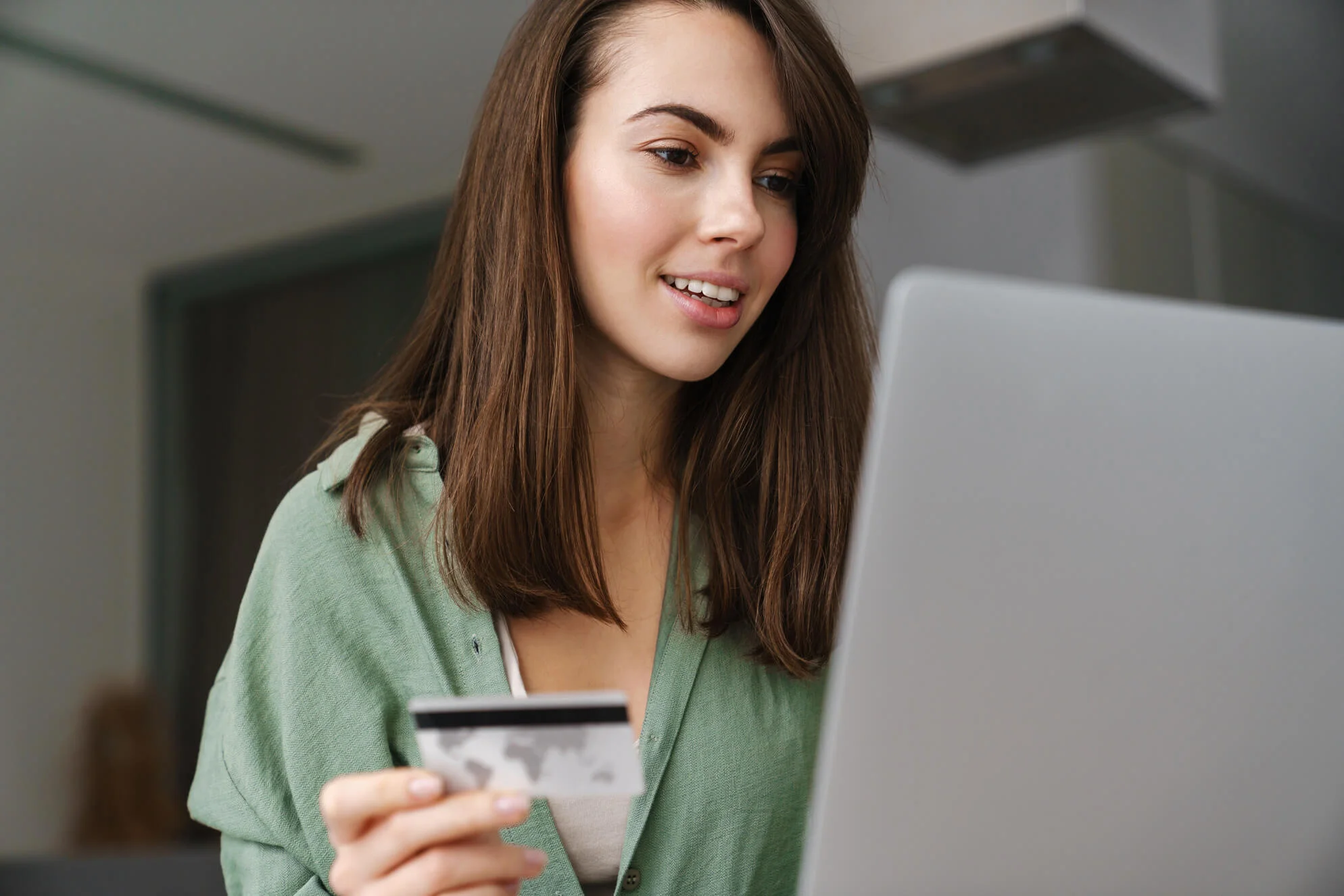 A person sitting by the laptop and holding a credit card in their hand